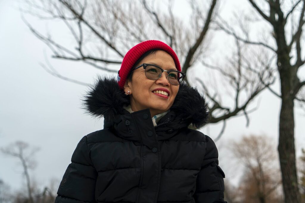 Photo of a Smiling Woman Wearing Black Winter Jacket and Red Woolen Cap