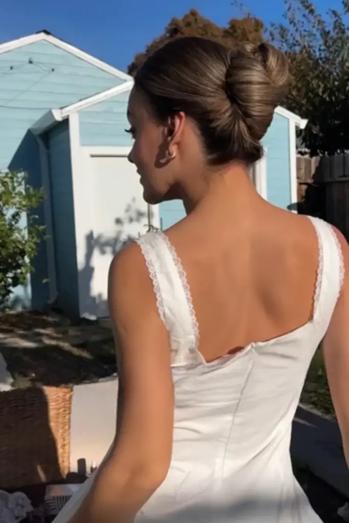 Young woman in white dress showing a sleek French Twist hairstyle