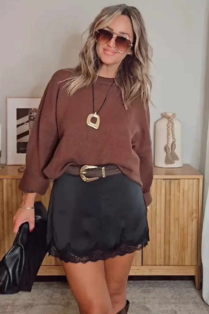 Fall mini skirt outfit inspiration with a black satin skirt styled witha brown top