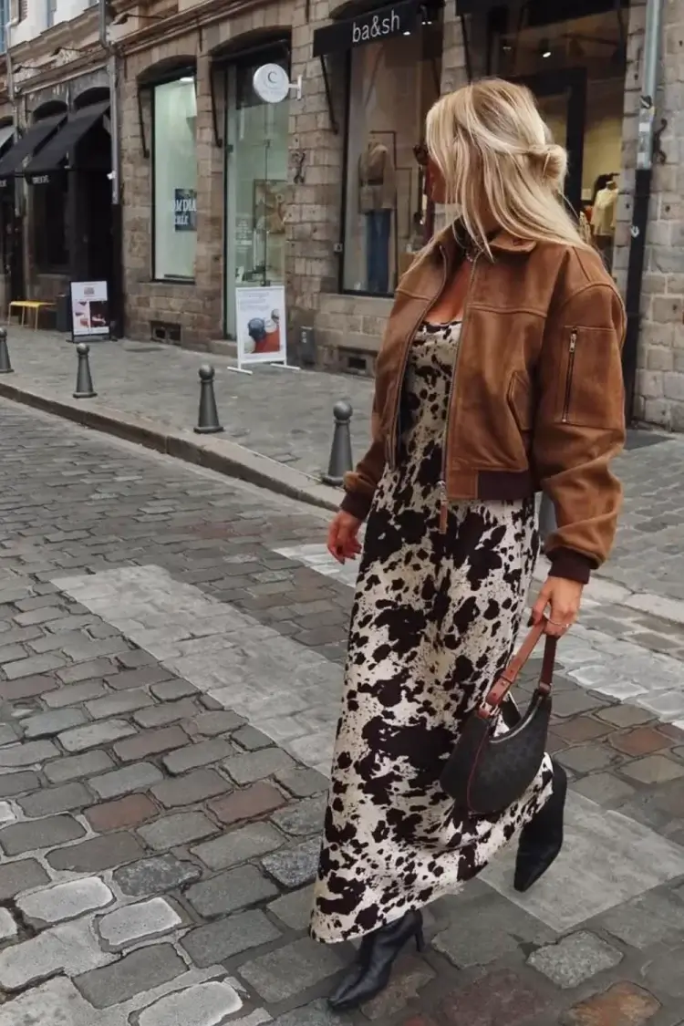 woman wearing cow print satin maxi dress and suede brown bomber jacket