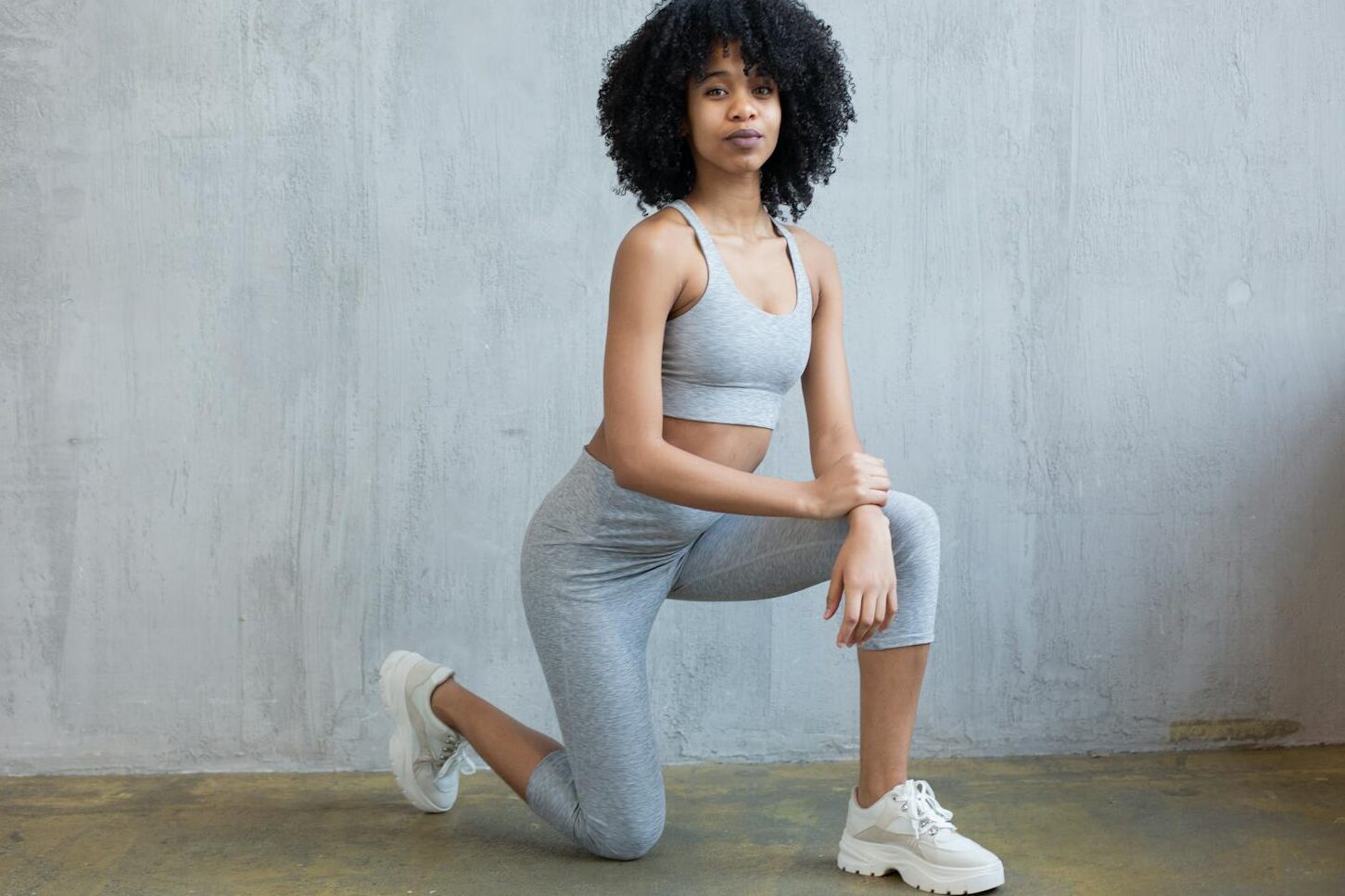 Black woman in sportswear doing lunge exercise