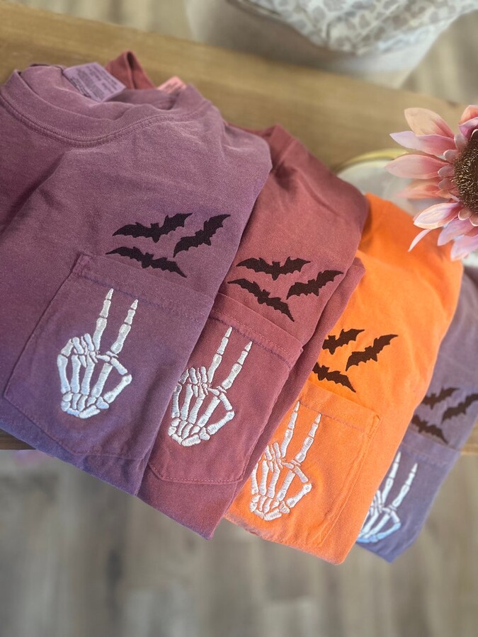 stack of Halloween shirts with bats and skeleton hands