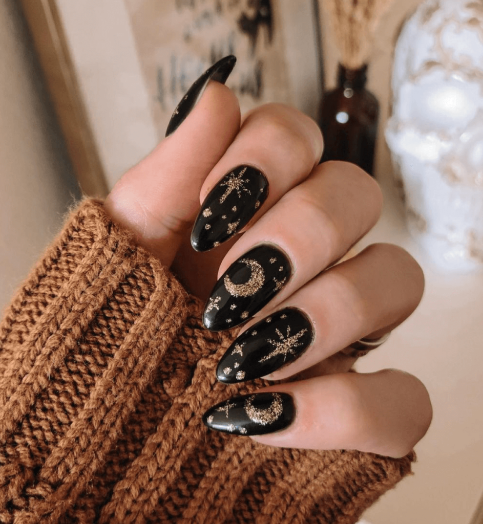 black nail polish with gold glitter moon and star design