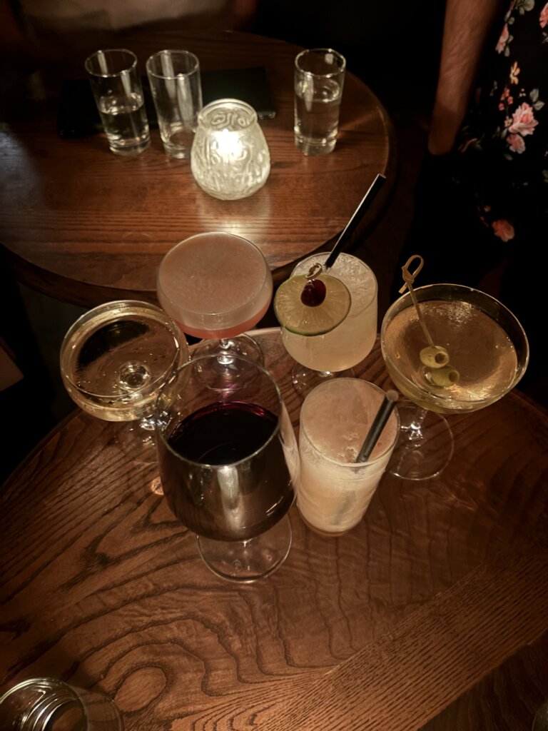 different cocktails sitting on wood table in low lighting