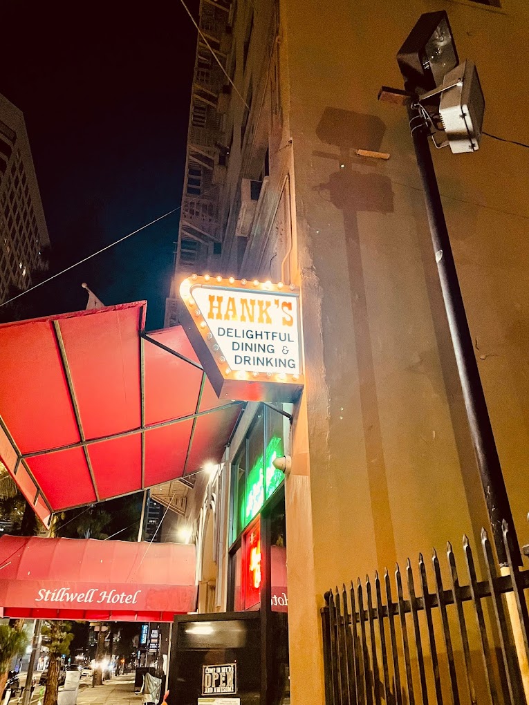 Sign of Hank's bar and slight view of Stillwell Hotel canopy