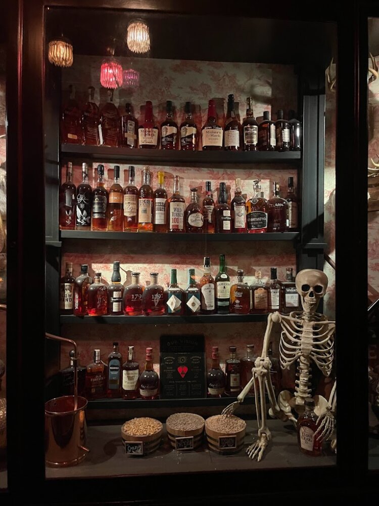 bar stocked with different liquor bottles with skeleton in corner