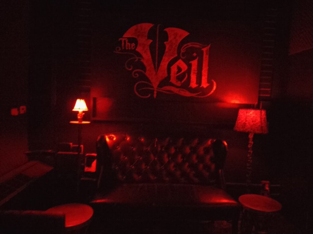 dark wall with red lighting with the word Veil painted on