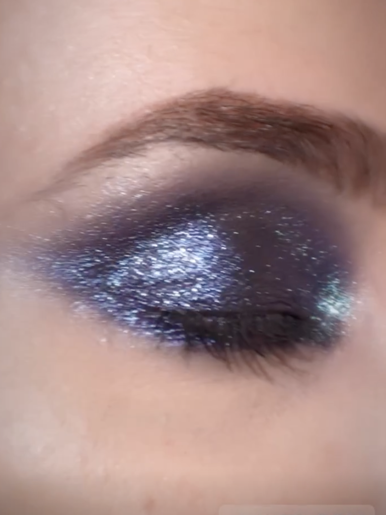 close up of dark glittery eye makeup on a single eye