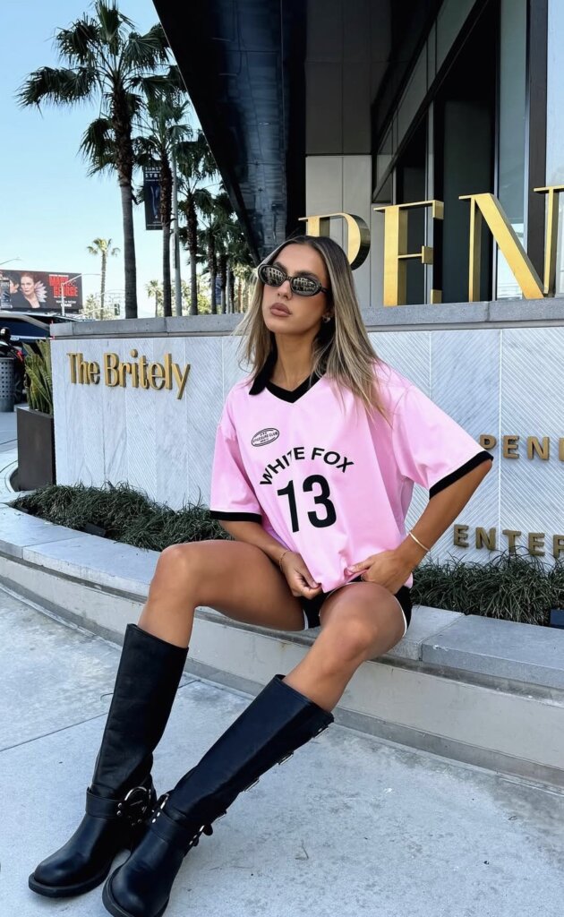 young woman wearing bright pink jersey and black boots