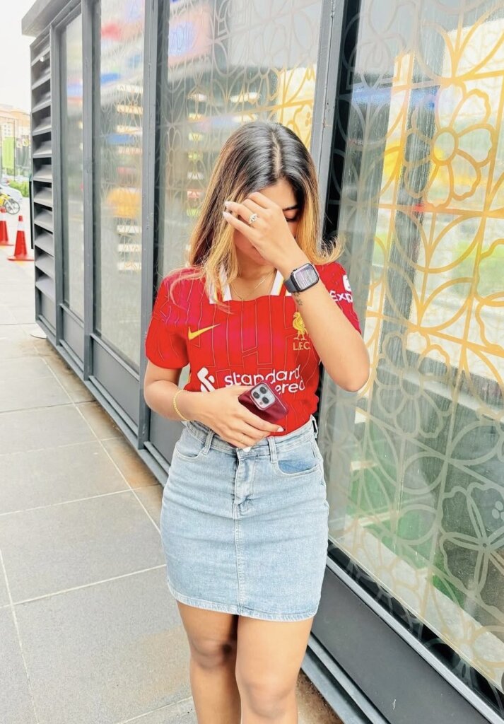 woman wearing a fitted red sports jersey tucked into a denim mini skirt