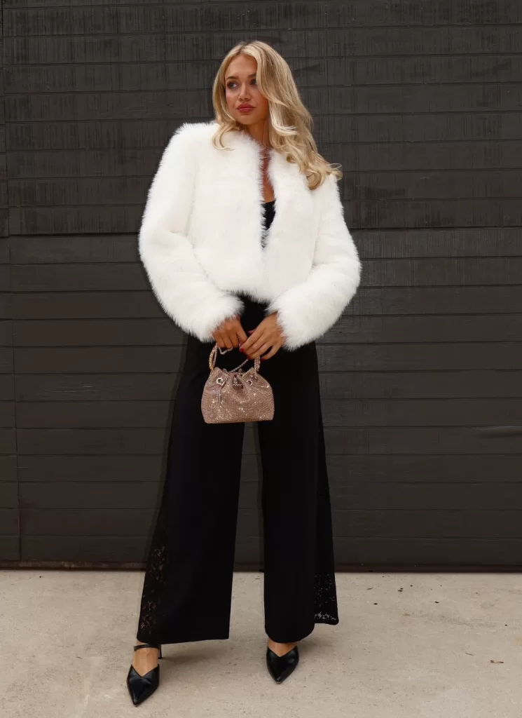 woman wearing all black velvet outfit with white cropped faux fur coat