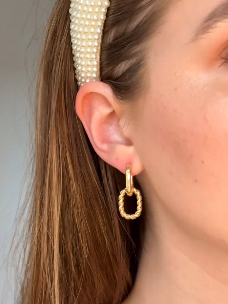 close up of gold earring with pearl headband