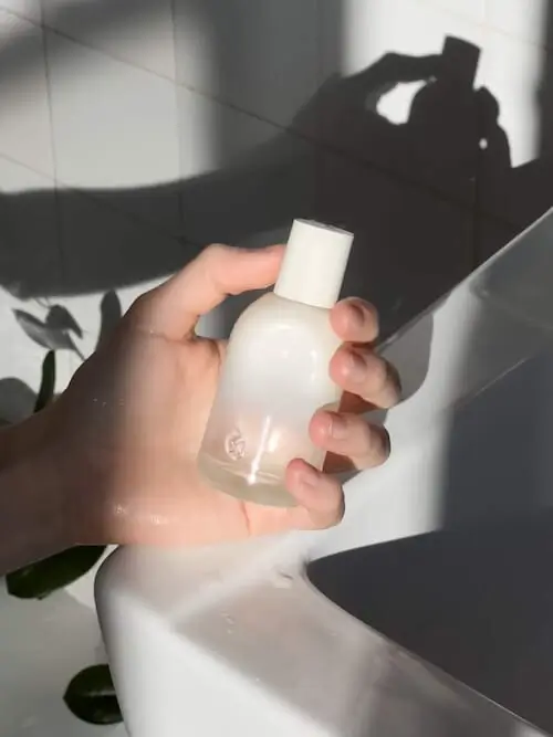 Glossier winter perfume in white bottle held up in light