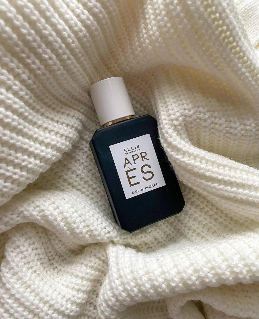 Apres black bottle of perfume against white sweater