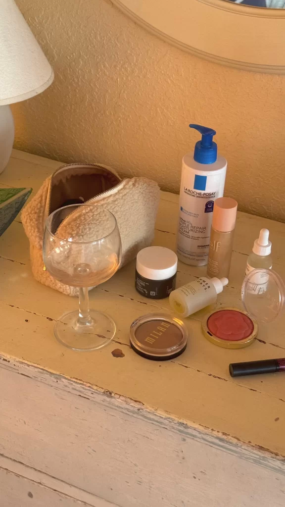 essential skincare and beauty products laid on on dresser with warm lighting