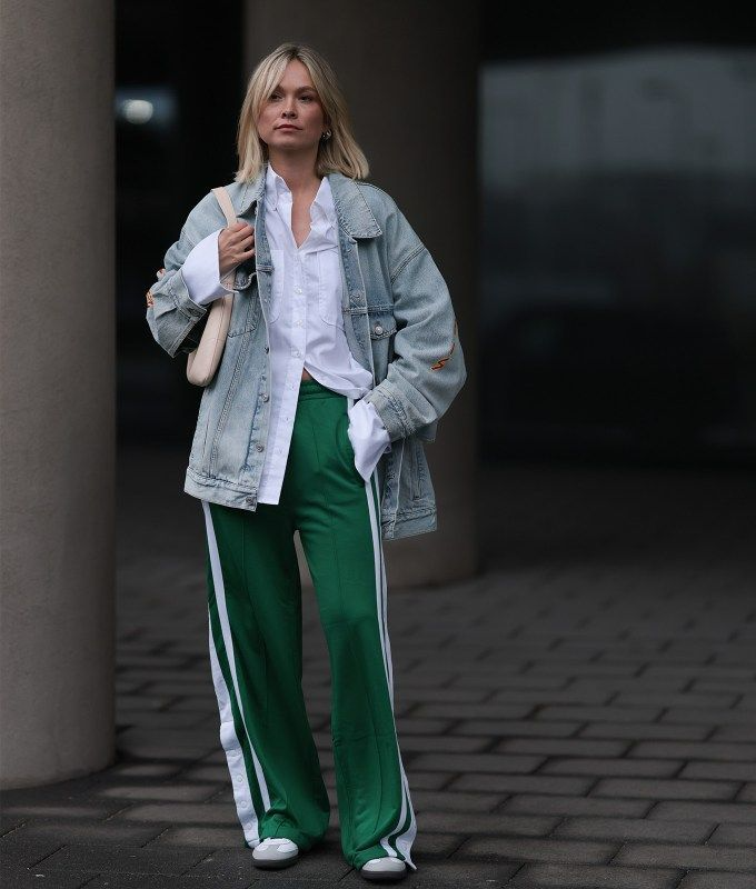 woman wearing white button down, denim jacket and baggy green track pants