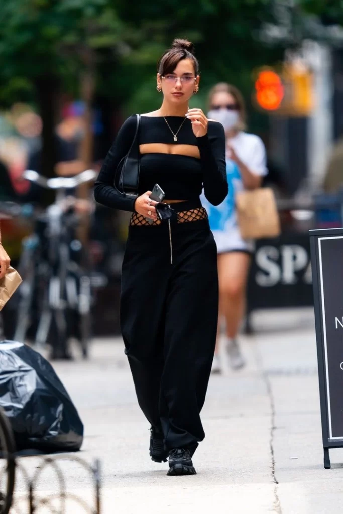 Singer Dua Lipa wearing all black sweatpants outfit walking down street