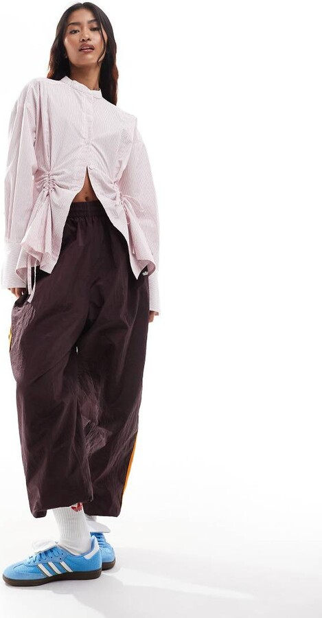 Asos model wearing ruched detailed long sleeve top and burgundy cargo pants