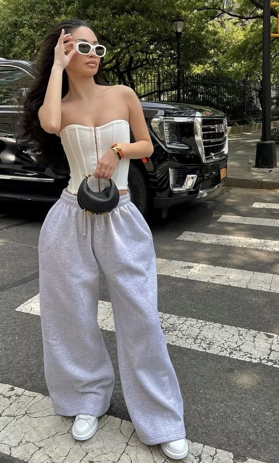 woman on busy street wearing strapless corset top and grey sweats