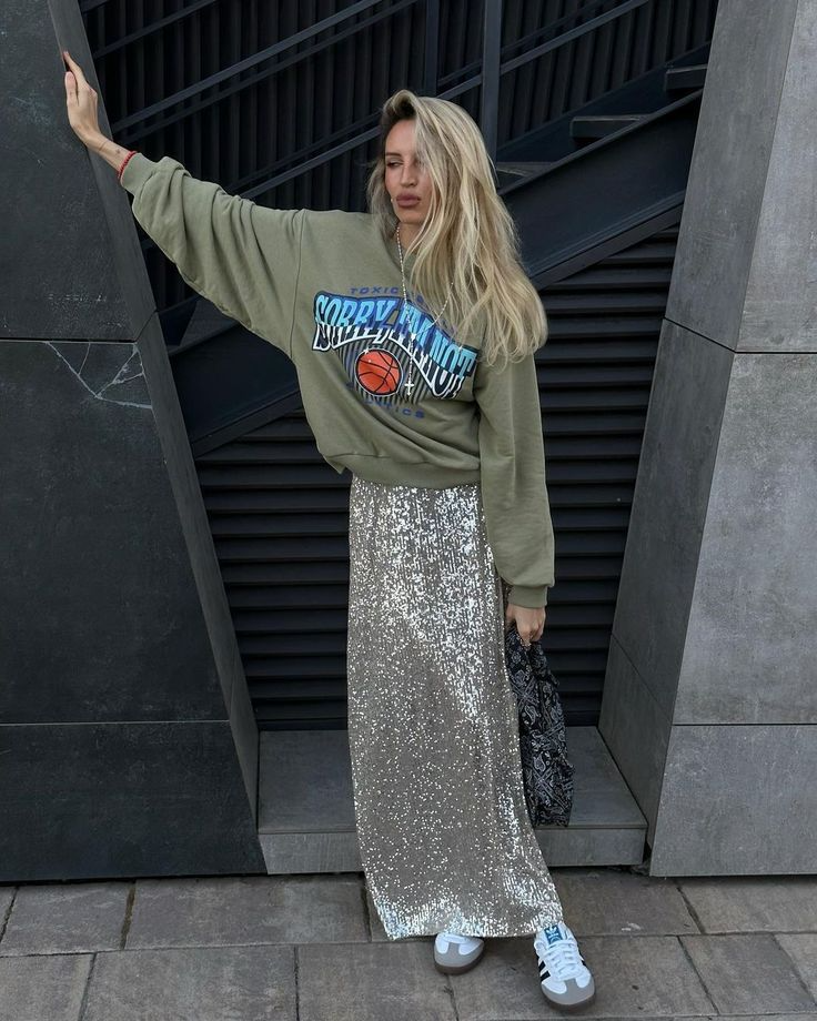 young blonde woman wearing graphic sports sweatshirt and maxi sequin skirt