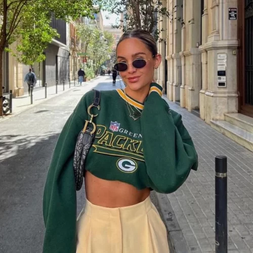 young woman wearing long sleeve Packers top cropped with high waisted trousers