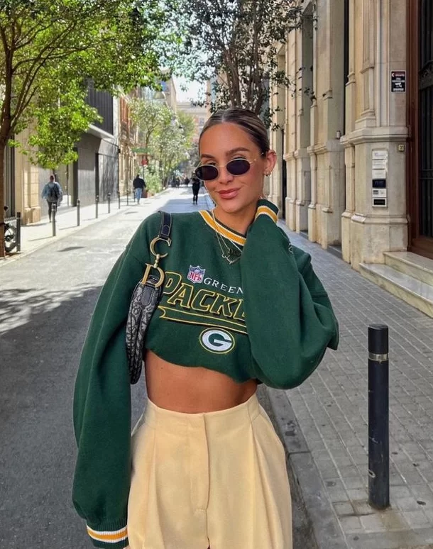 young woman wearing long sleeve Packers top cropped with high waisted trousers