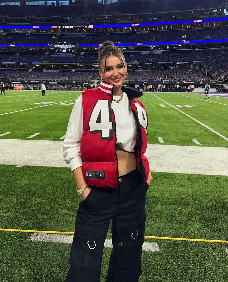 Designer and influencer Kristin Juszczyk posing on football field in one of her custom game day puffer jackets