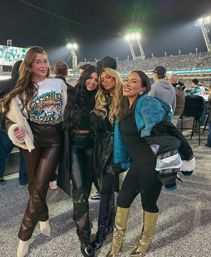 group of woman posing at a football game wearing luxe game day outfits including metallic knee high boots