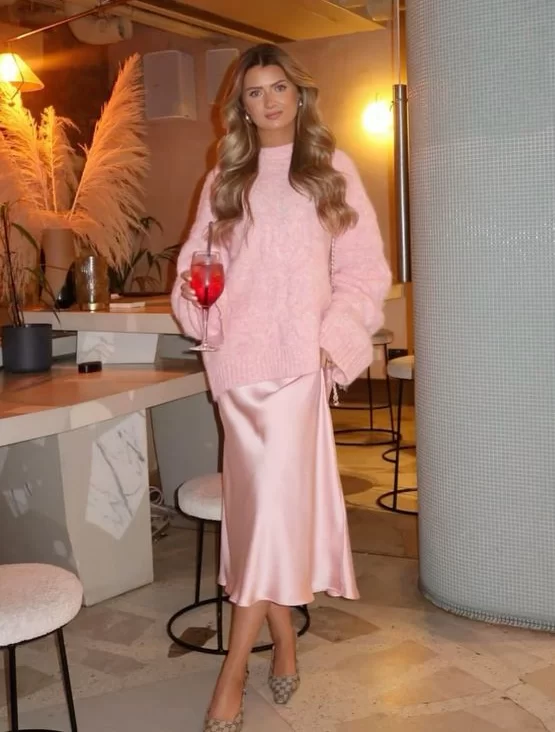 young blonde woman in monochromatic pink sweater and satin skirt outfit for winter date night