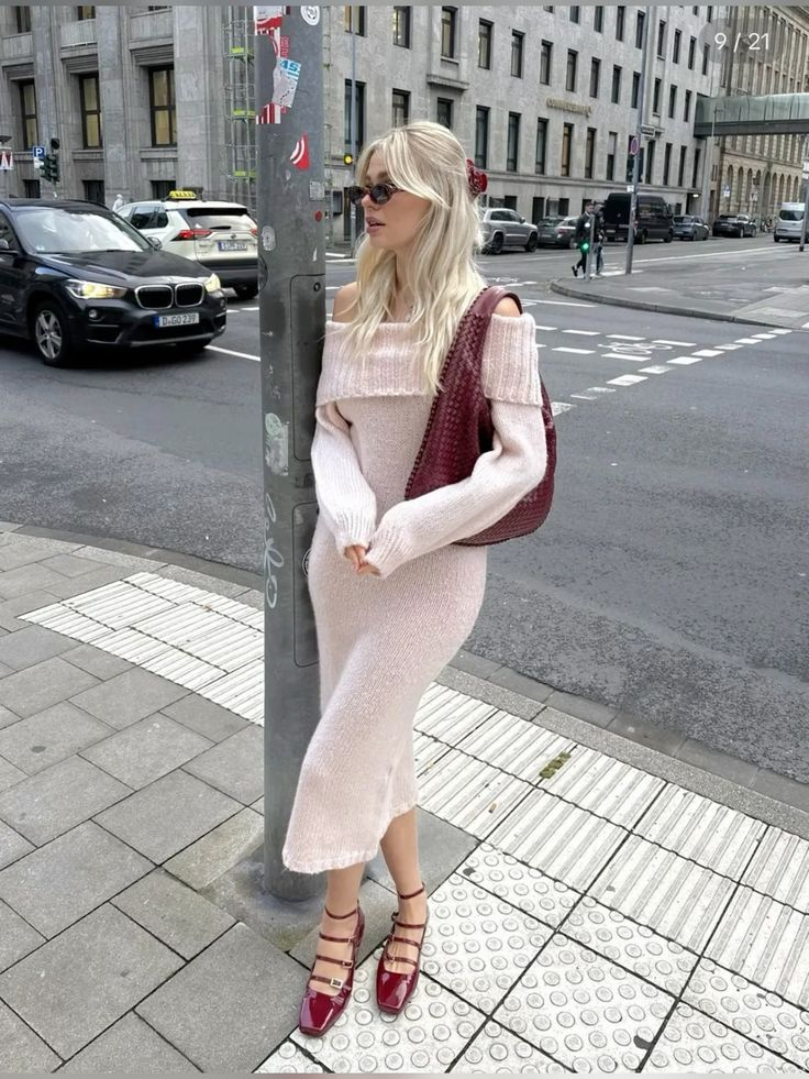 blonde woman wearing pink off the shoulder sweater dress with red accessories