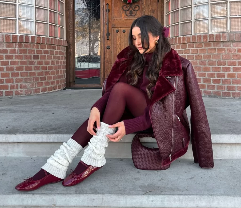 Young woman sitting on stairs in burgundy winter outfit