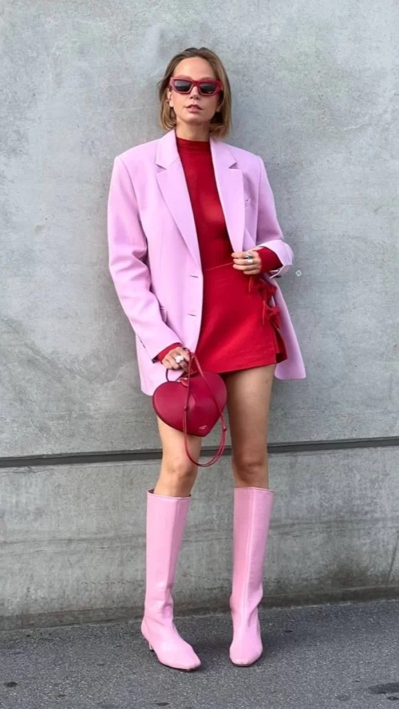 young woman wearing colorblock Valentine's day ensemble winter with red dress and pink blazer and boots