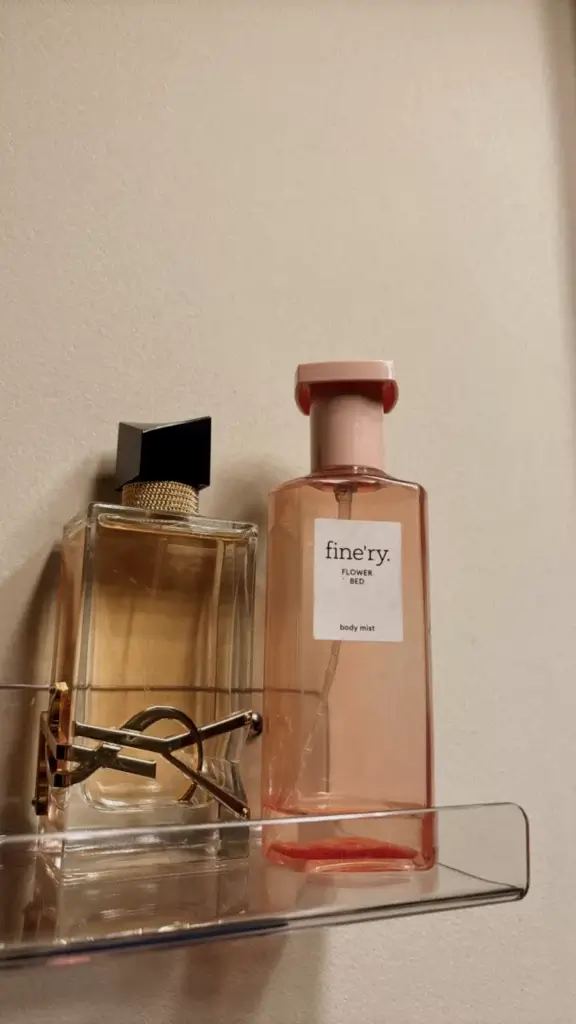Close up shot of budget spring perfume from Fin'ery next to YSL perfume bottle on acrylic holder