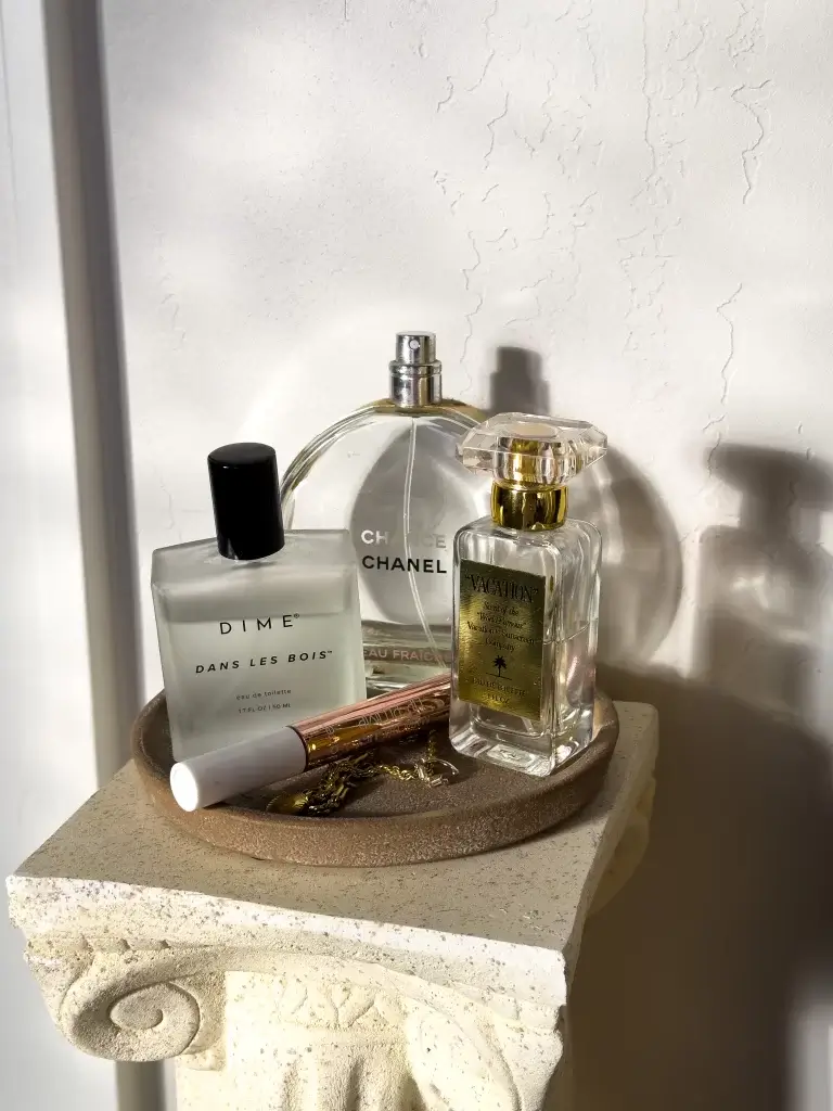 golden hour shot of three different perfume bottles on marble stand against wall