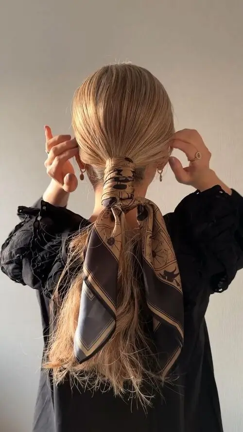 blonde woman with low pony tail wrapped up in a silk scarf