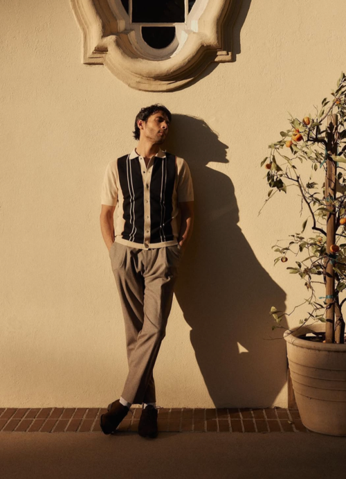 model posing against golden hour background wall wearing knitted short sleeve button down and chinos