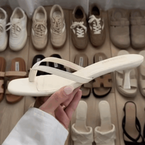 Close up a white heeled thong sandal with a background of some of the best summer shoes for women behind it