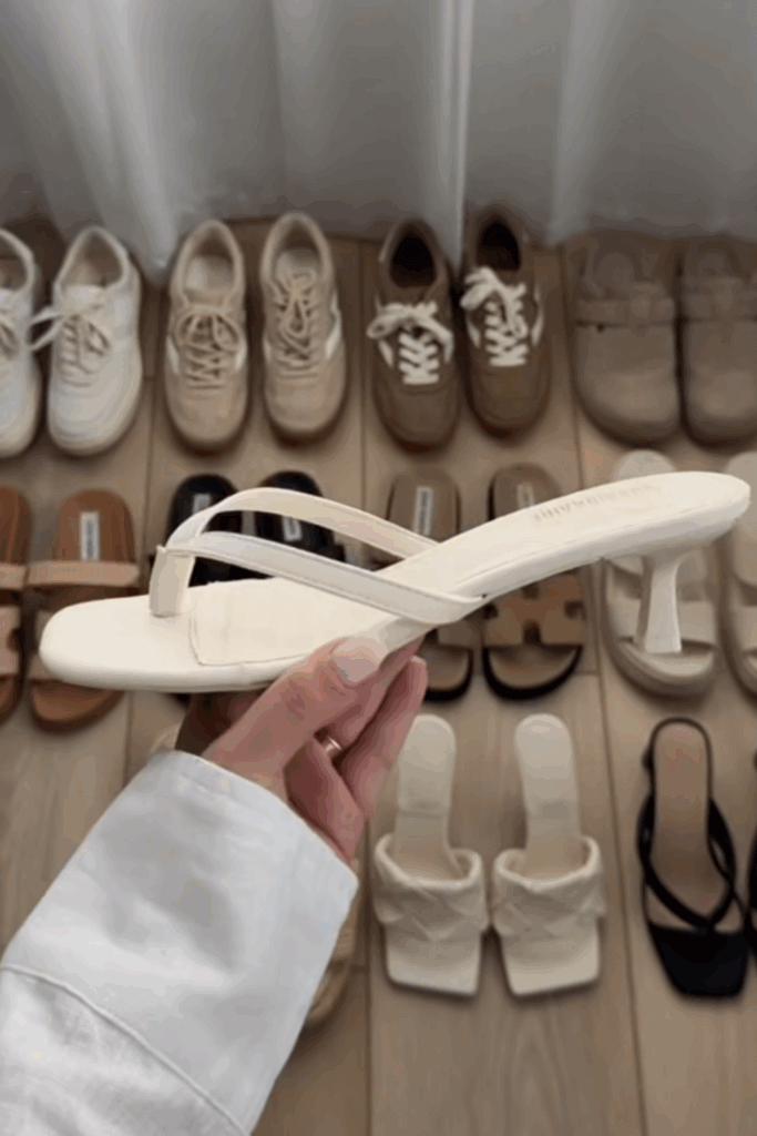 Close up a white heeled thong sandal with a background of some of the best summer shoes for women behind it