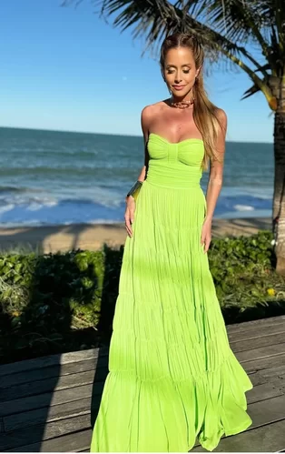 bright and bold neon green boho style wedding guest outfit idea worn by a young woman with a ocean background