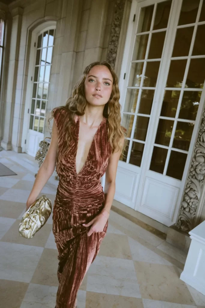 model posing in bronze velvet low plunging gown as a wedding guest outfit
