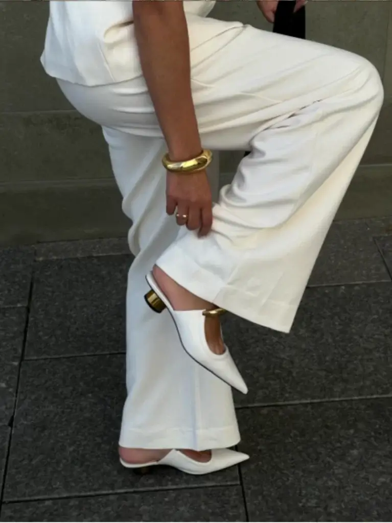 cropped photo of woman adjusting pants while showing off work appropriate summer outfit with summer shoes