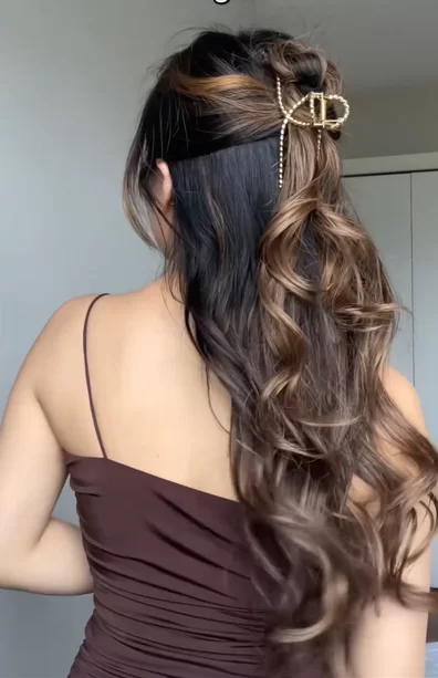 cute hairstyle for date night with soft curls and half up twisted and secured with gold metal claw clip