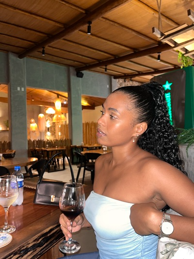 Young black woman sitting at restaurant with her natural hair styled perfect for a date night accented with green ribbon 
