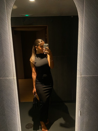 woman taking selfie in dark lit bathroom mirror showing off her date night look
