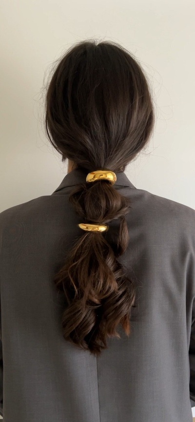 woman wearing hair in low ponytail with bold metal hair ties accessorizing her hairstyle
