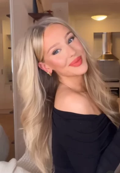 young blonde woman showing her soft romantic hairstyle with her bangs tucked tightly back behind her ears