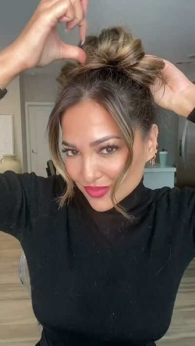 woman in the process of showing how she makes her perfect messy bun by pulling out certain sections to enlarge it