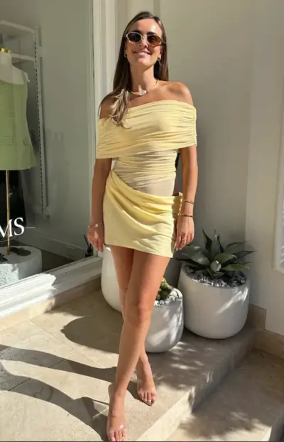 woman standing in sunlight wearing off the shoulder mesh yellow mini dress for date night