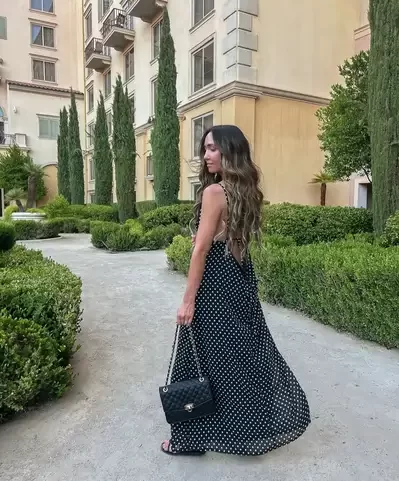 woman walking in garden wearing a trendy polka dot summer dress for a date night outfit