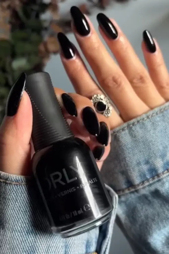 classic black nail manicure on almond shaped nails with picture of nail polish bottle